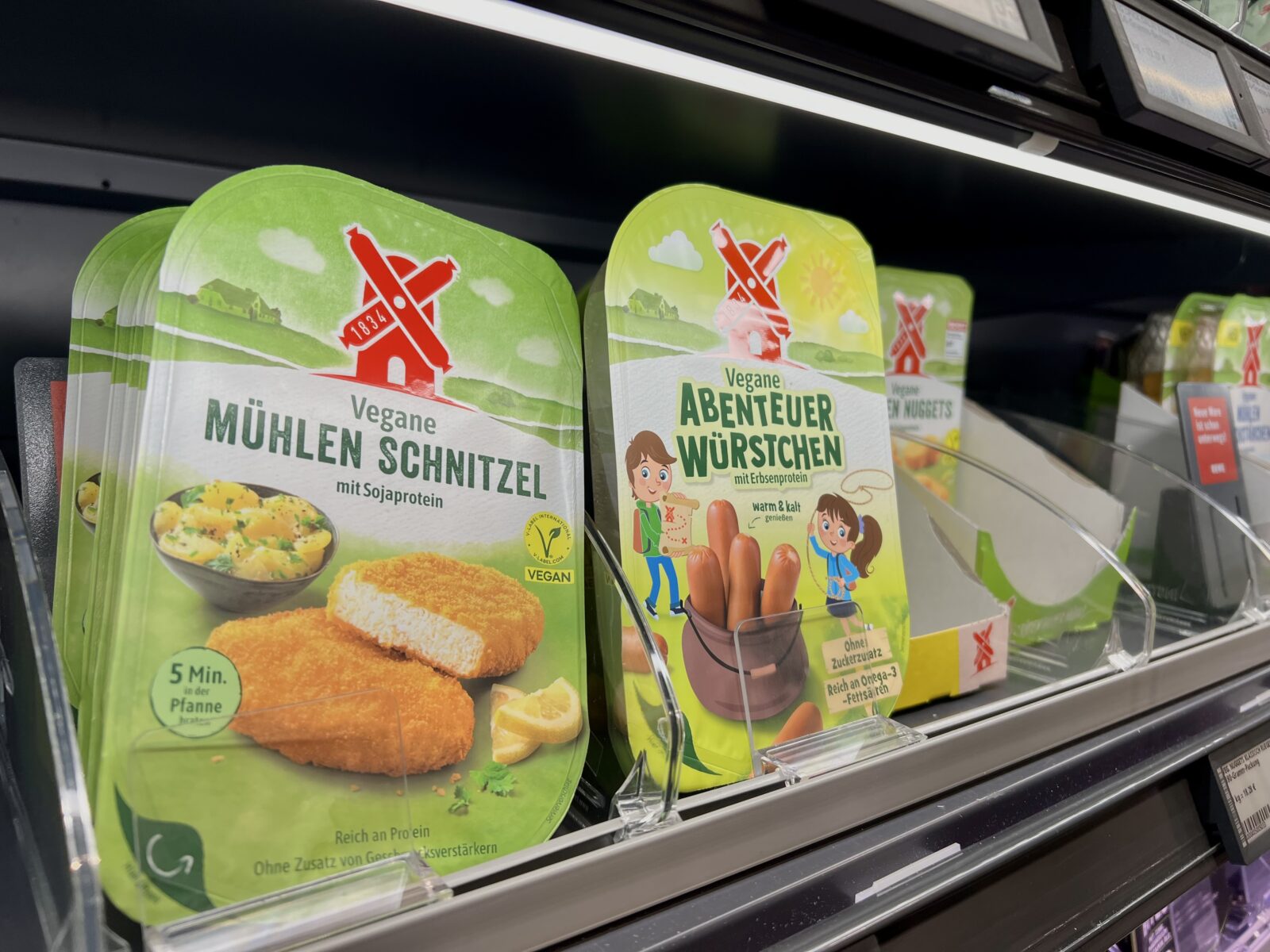 Vegane Mühlen Schnitzel und vegane Abenteuer Würstchen im Regal eines Supermarktes.